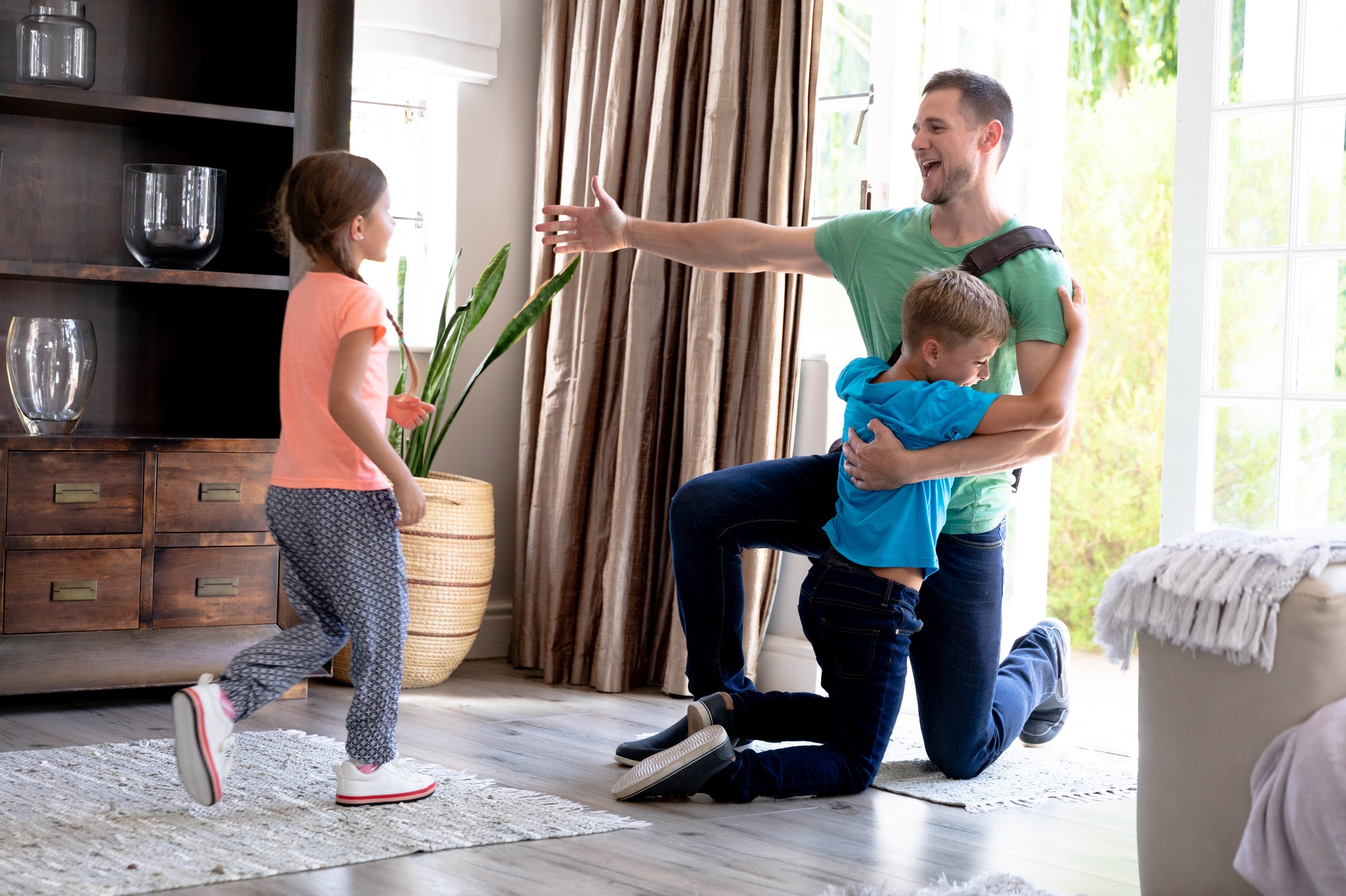 Caucasian girl and boy welcoming their father in their house.