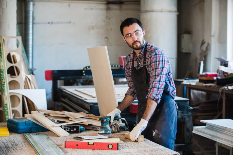 Worker grinds the wood of angular grinding machine