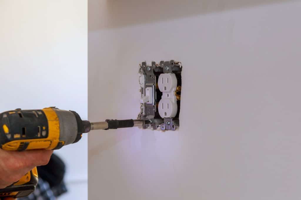 Electrician repairing wall switch indoors a newly kitchen wall.