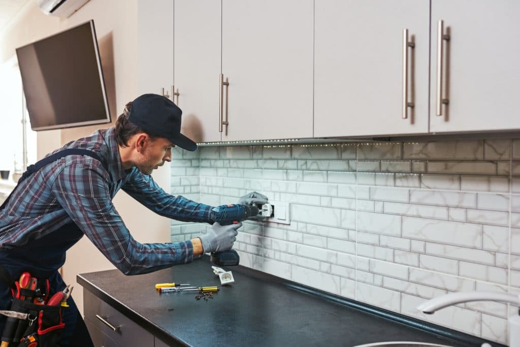 Electricity protection. Side view of young handyman with perforator