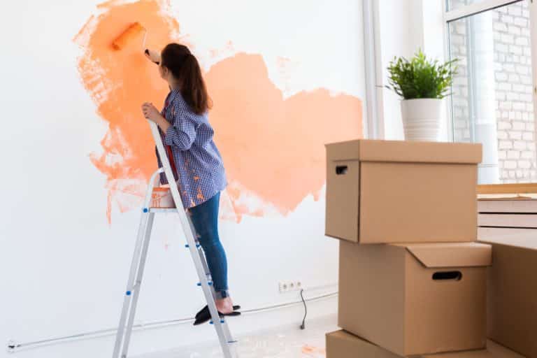 Cheerful woman painting the walls of new home. Renovation, repair and redecoration concept