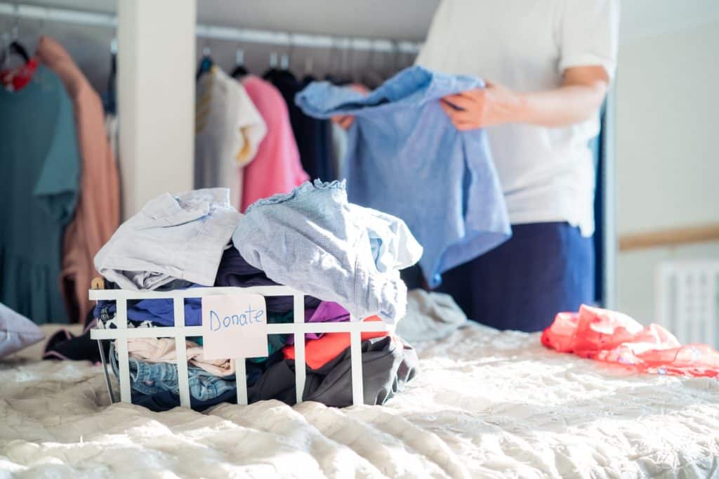 Woman cleaning and checking her wardrobe for donating clothes to a Charity shop. Reuse, second hand.