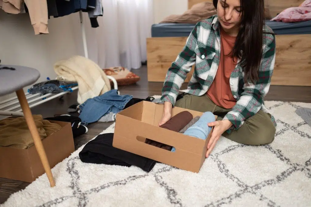 woman organizing clothes in box, packing clothes in boxes, cleaning up, putting away things