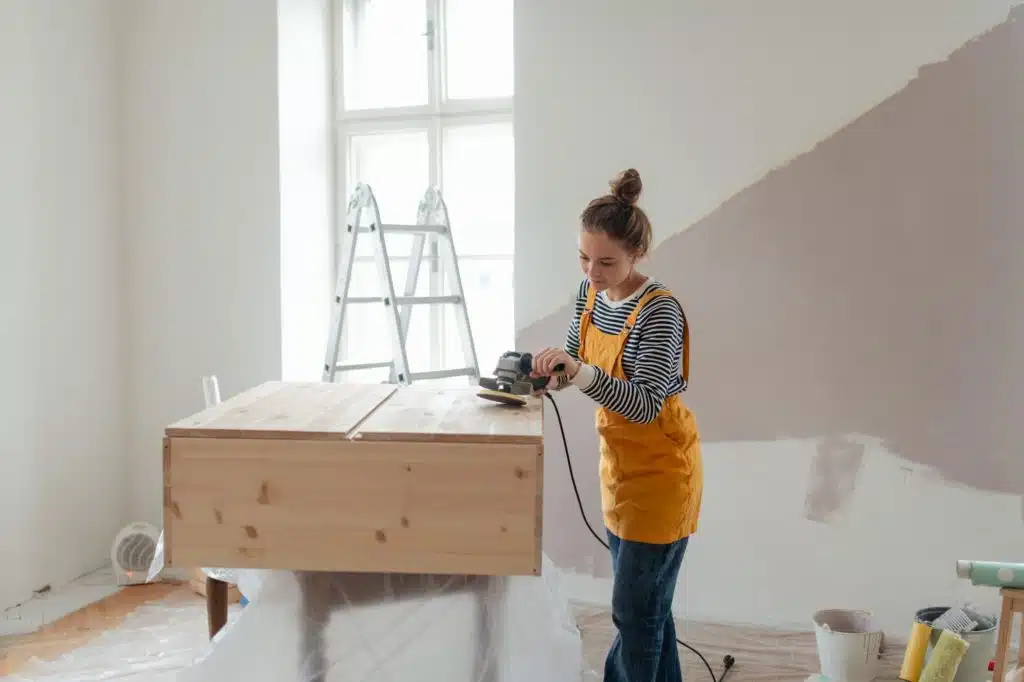 Happy young woman remaking wooden cabinet in her new flat. Concept of reusing materials and
